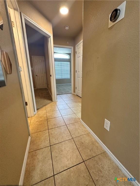 corridor with light tile patterned flooring and baseboards