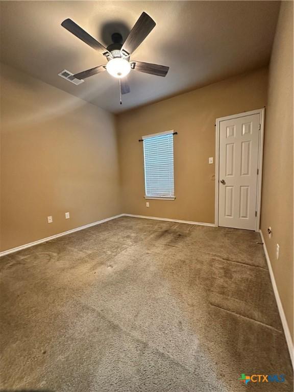 unfurnished room with carpet floors, ceiling fan, visible vents, and baseboards