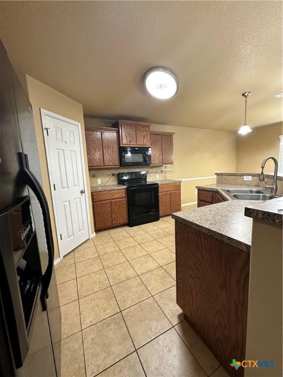 kitchen featuring pendant lighting, light tile patterned floors, a sink, a textured ceiling, and black appliances