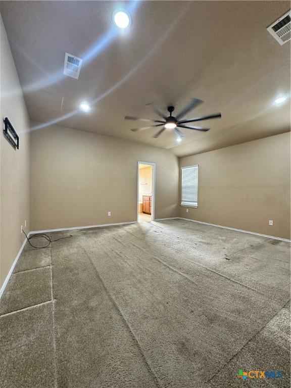 carpeted spare room featuring baseboards, visible vents, and a ceiling fan