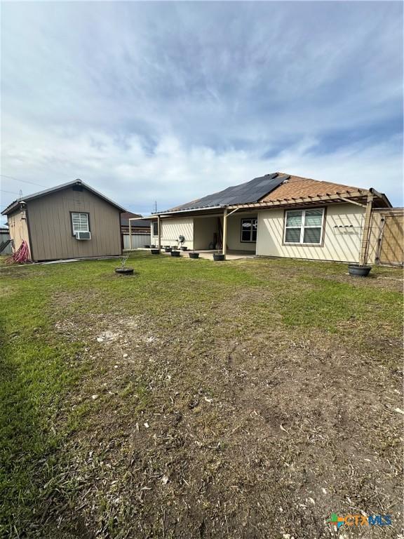 back of house with a patio, a lawn, fence, and solar panels