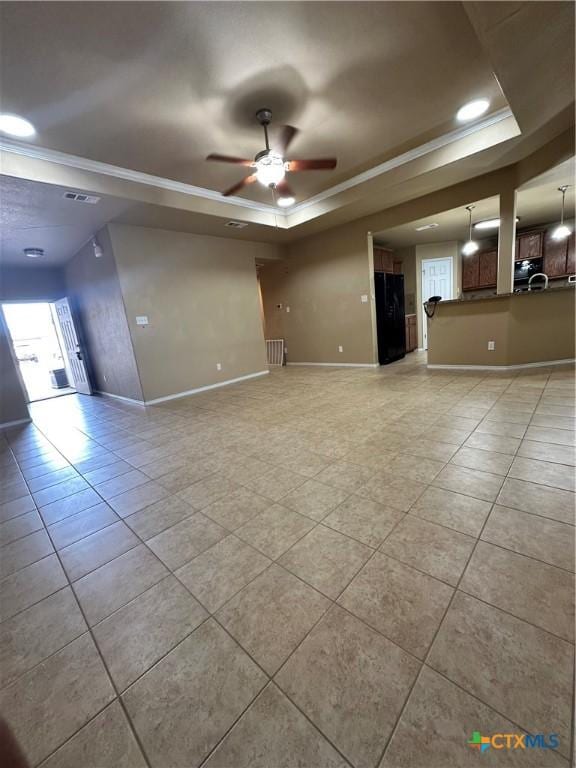 unfurnished living room with ornamental molding, a tray ceiling, and baseboards