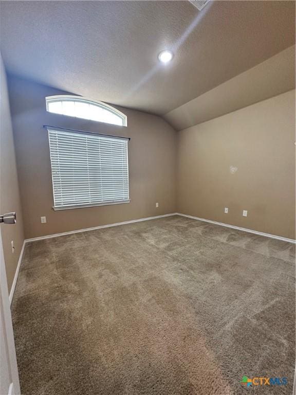 spare room featuring lofted ceiling, carpet floors, a textured ceiling, and baseboards