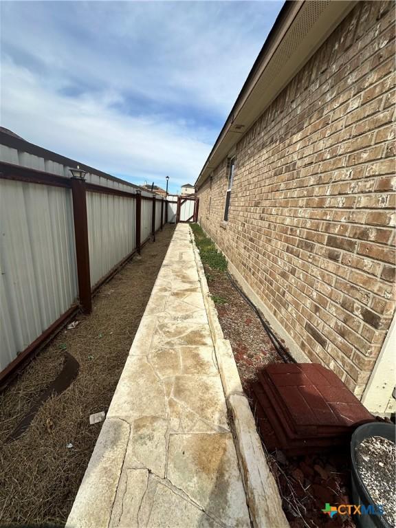 view of side of home with brick siding and a fenced backyard