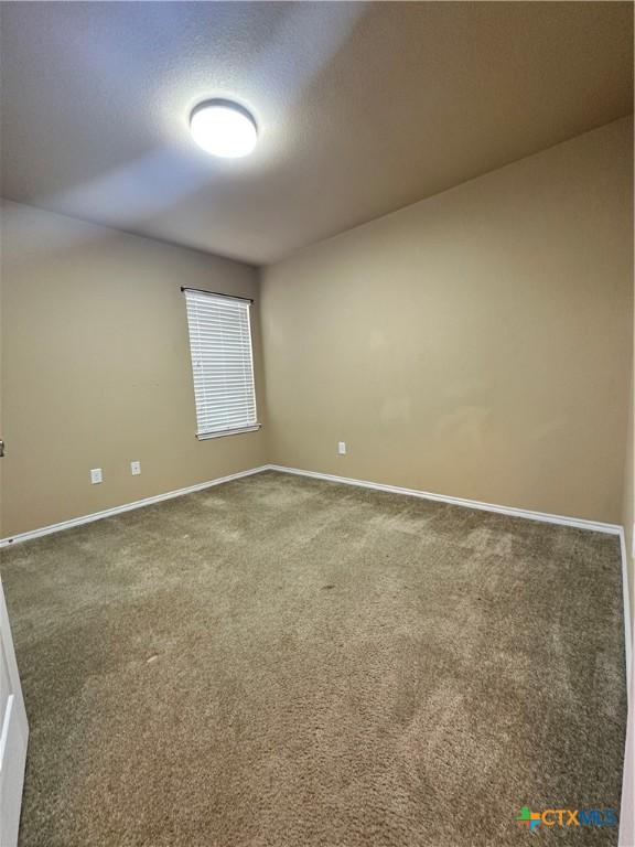 empty room featuring carpet and baseboards