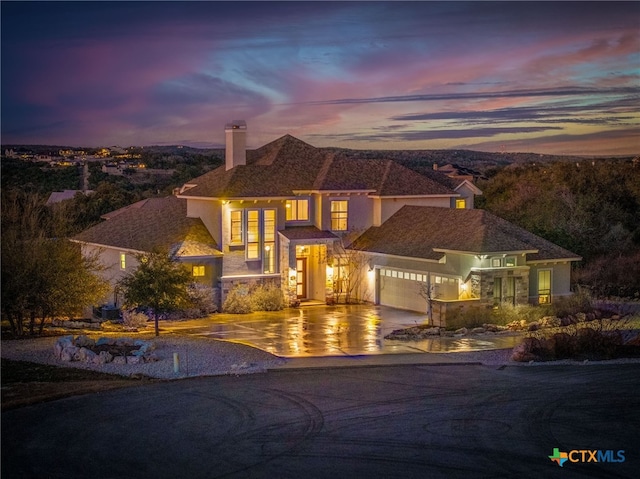 view of front of house with a garage, concrete driveway, a chimney, and stucco siding