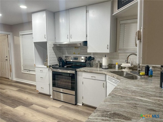 kitchen with stainless steel electric stove, light wood-type flooring, under cabinet range hood, and a sink