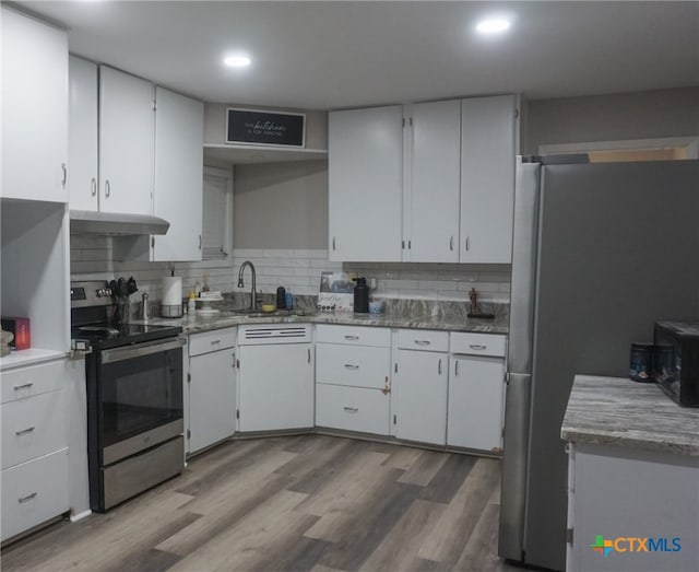 kitchen with white cabinets, hardwood / wood-style floors, stainless steel appliances, and tasteful backsplash