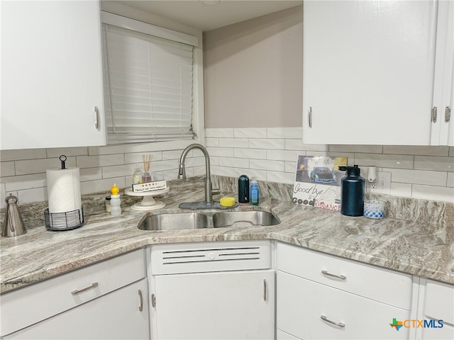 kitchen featuring white cabinets, decorative backsplash, light stone counters, and sink