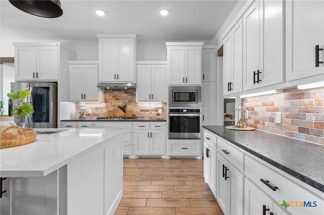 2037 Heritage Loop, Nolanville, TX 76559 - kitchen with stainless steel appliances, decorative backsplash, white cabinets, under cabinet range hood, and recessed lighting