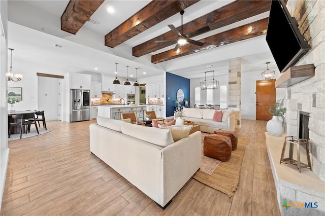 2037 Heritage Loop, Nolanville, TX 76559 - living room featuring a chandelier, ceiling fan, beamed ceiling, light wood finished floors, and a stone fireplace