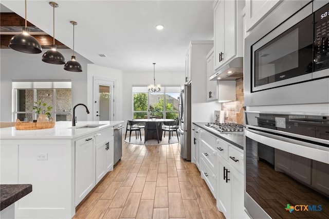 2037 Heritage Loop, Nolanville, TX 76559 - kitchen featuring appliances with stainless steel finishes, backsplash, a chandelier, white cabinets, and light wood-type flooring