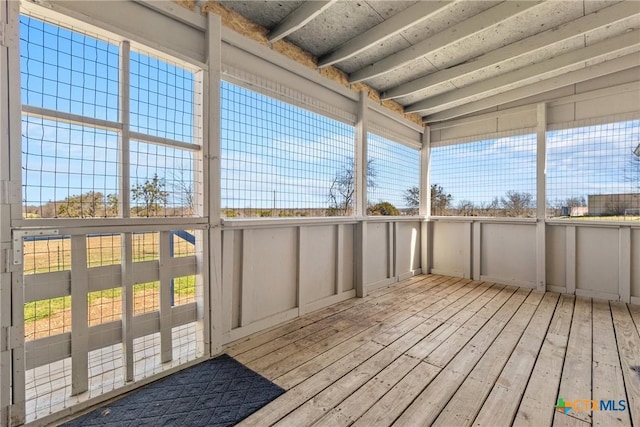 unfurnished sunroom with a healthy amount of sunlight and beamed ceiling