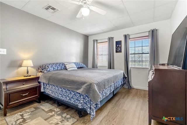 bedroom featuring wood finished floors, visible vents, and a ceiling fan