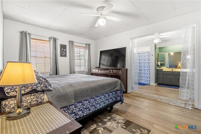 bedroom with light wood-type flooring, baseboards, a ceiling fan, and ensuite bathroom