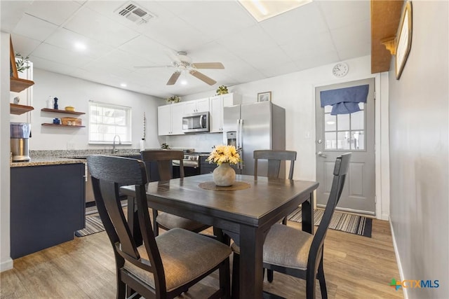 dining space with light wood finished floors, ceiling fan, and visible vents