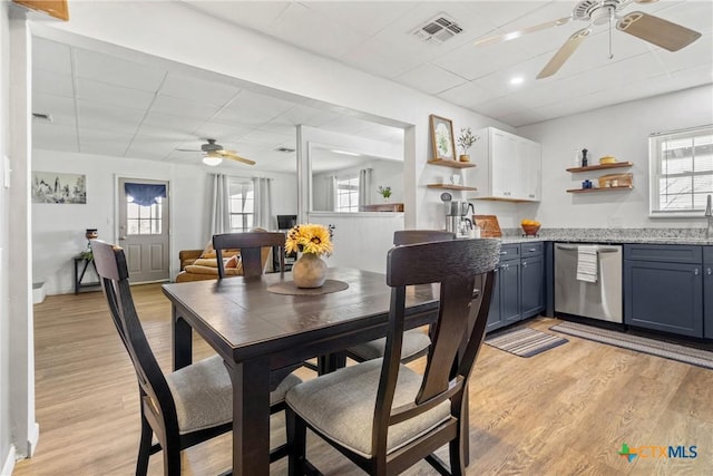 dining space with light wood-style floors, visible vents, and a drop ceiling