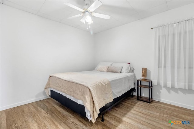 bedroom with a ceiling fan, baseboards, and wood finished floors