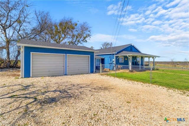 view of front of house featuring a garage, an outbuilding, fence, and a front lawn