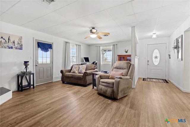 living area featuring baseboards, a paneled ceiling, visible vents, and light wood-style floors