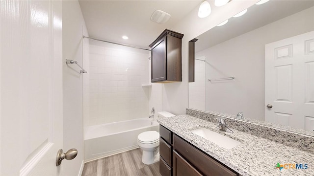 full bathroom featuring tiled shower / bath, wood-type flooring, toilet, and vanity