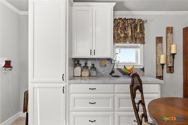 bar featuring ornamental molding and white cabinets