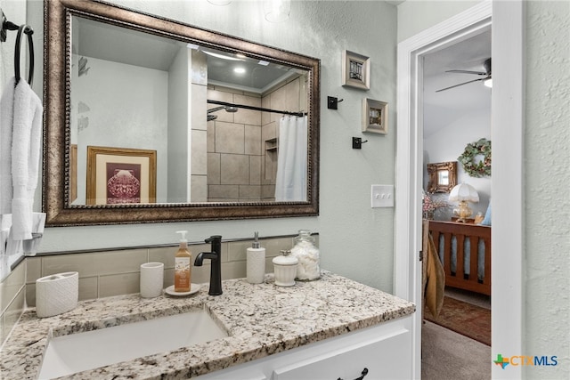 bathroom with walk in shower, ceiling fan, and vanity