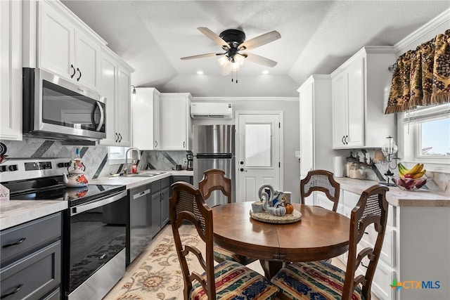 kitchen with gray cabinets, appliances with stainless steel finishes, vaulted ceiling, and white cabinets