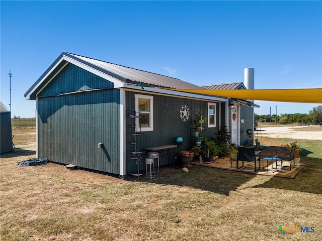 rear view of property with an outdoor structure, a patio, and a yard