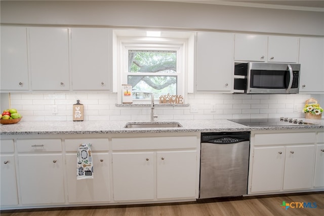 kitchen with white cabinetry, stainless steel appliances, sink, and decorative backsplash