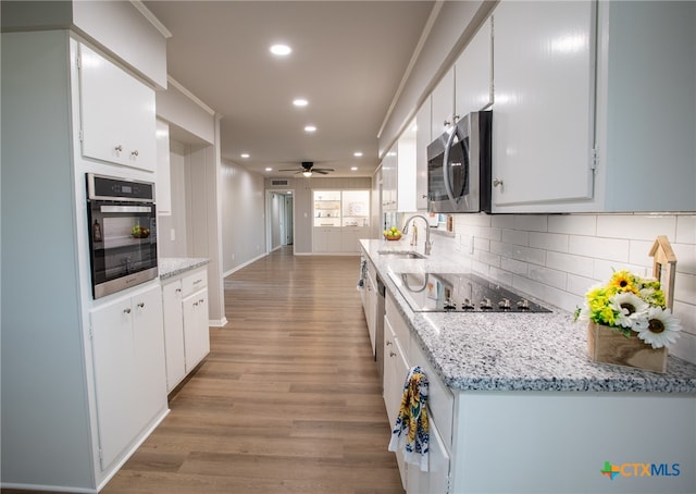 kitchen with sink, ceiling fan, white cabinetry, backsplash, and stainless steel appliances