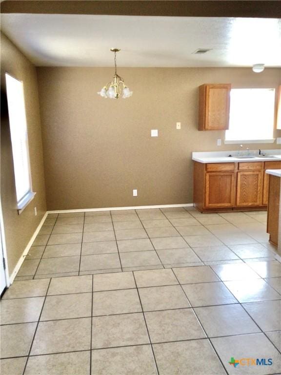 kitchen with pendant lighting, a healthy amount of sunlight, an inviting chandelier, and light tile patterned floors