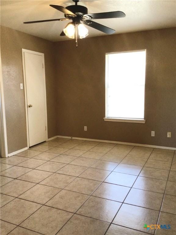 tiled empty room featuring ceiling fan