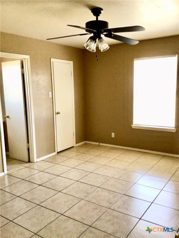 tiled empty room featuring ceiling fan