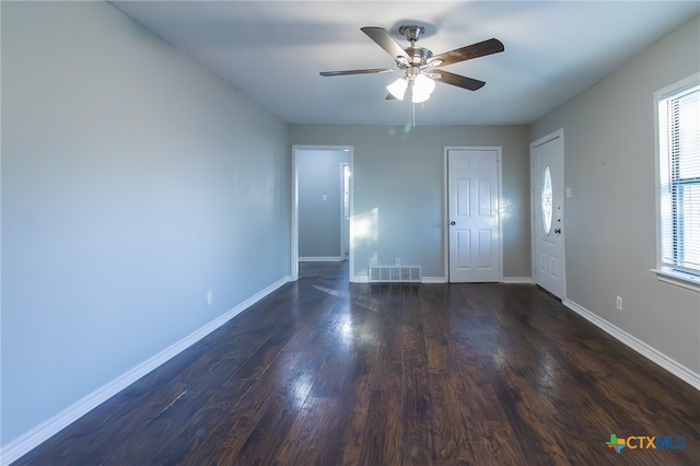 empty room featuring ceiling fan, dark hardwood / wood-style floors, and plenty of natural light