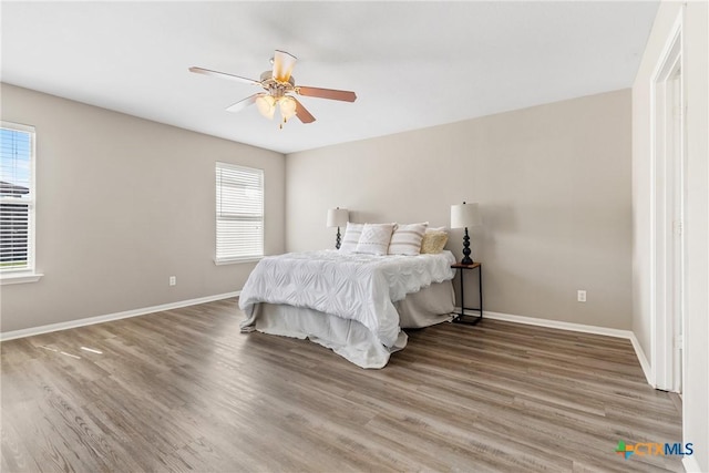 bedroom with a ceiling fan, baseboards, and wood finished floors