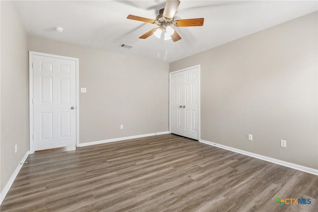 spare room with a ceiling fan, wood finished floors, visible vents, and baseboards