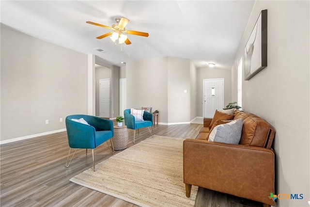 living area featuring visible vents, baseboards, wood finished floors, and a ceiling fan