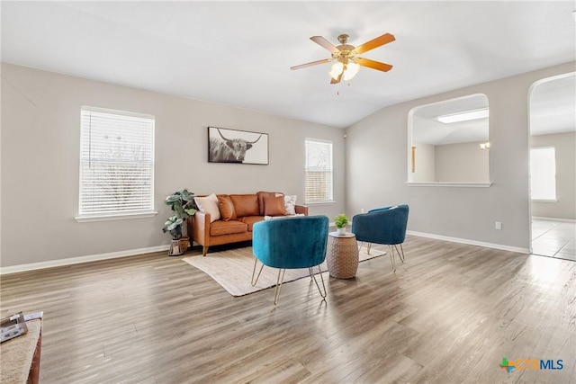 living room with a wealth of natural light, a ceiling fan, baseboards, and wood finished floors