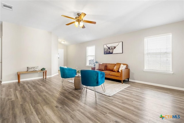 living area featuring visible vents, baseboards, wood finished floors, and vaulted ceiling