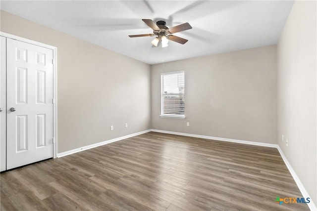 unfurnished room featuring baseboards, wood finished floors, and a ceiling fan