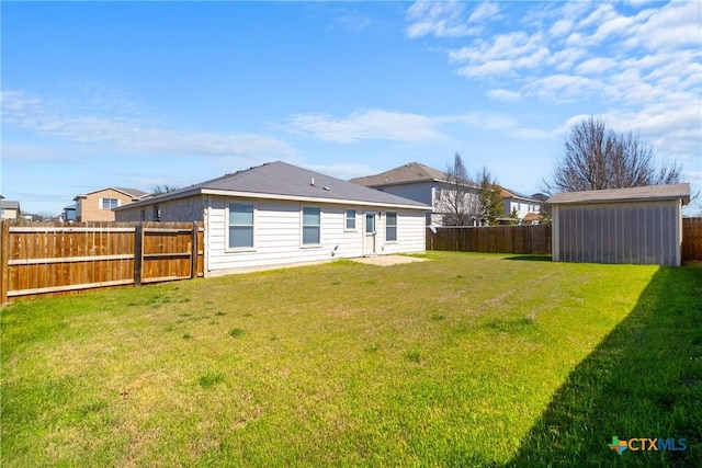 back of house with an outbuilding, a yard, and a fenced backyard