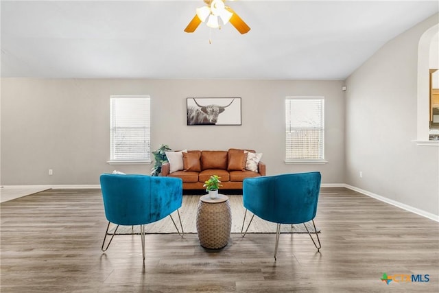 living area with a ceiling fan, baseboards, and wood finished floors