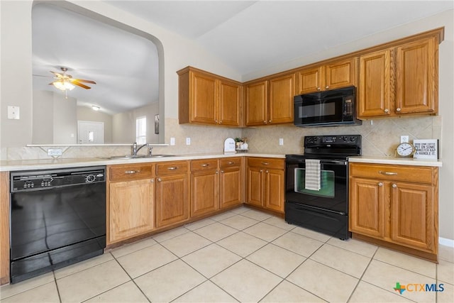 kitchen featuring black appliances, a sink, backsplash, light countertops, and vaulted ceiling