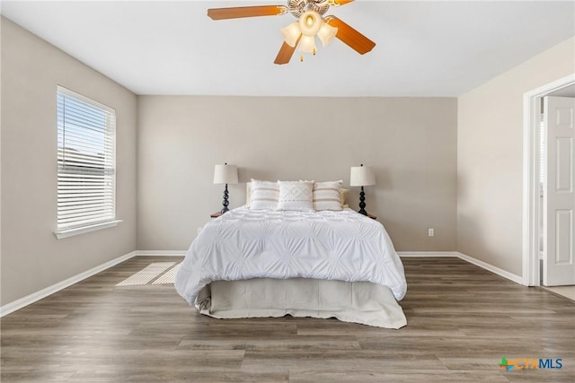 bedroom featuring ceiling fan, baseboards, and wood finished floors