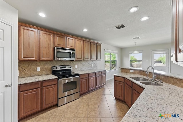 2441 Ibis Ave, New Braunfels, TX 78130 - kitchen with recessed lighting, brown cabinetry, decorative backsplash, stainless steel appliances, and a sink