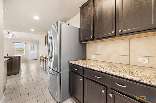 10055 Strasbourg Way, Schertz, TX 78154 - kitchen with freestanding refrigerator, dark brown cabinetry, backsplash, a ceiling fan, and light stone countertops