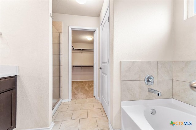10055 Strasbourg Way, Schertz, TX 78154 - bathroom with a garden tub, tile patterned flooring, a stall shower, a walk in closet, and vanity