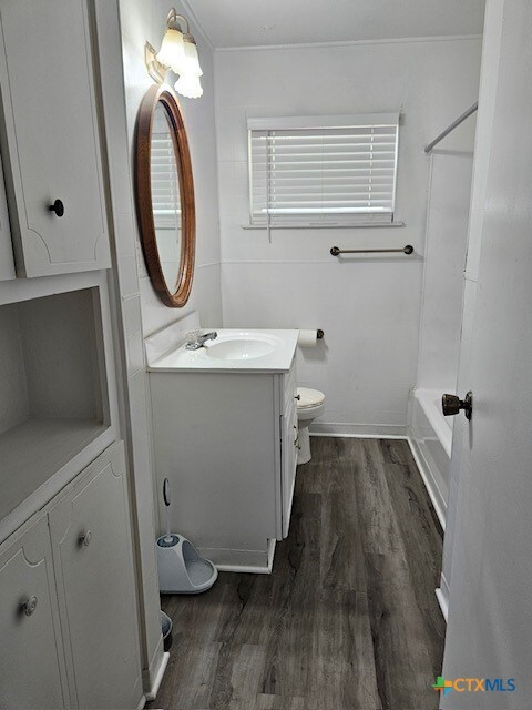 full bathroom with hardwood / wood-style floors, vanity, toilet, and shower / bath combination