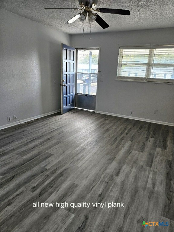 empty room featuring ceiling fan, a textured ceiling, and dark hardwood / wood-style flooring